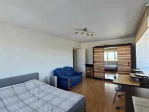 a bedroom with a bed and a blue chair and a desk at Hero Avenue Apartment in Narva