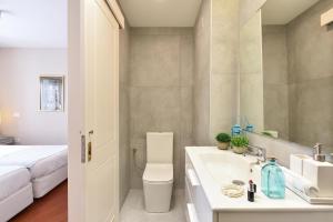 a bathroom with a sink and a toilet and a bed at Beach and View Arguineguin MG by VillaGranCanaria in Arguineguín