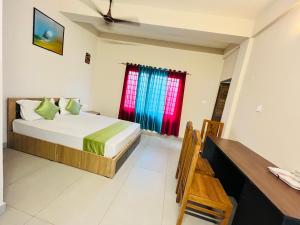 a bedroom with a bed and a desk and a window at Marhaba inn in Kozhikode