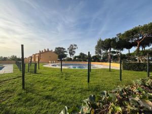 a row of poles in the grass near a swimming pool at La casa del verano in Isla Cristina
