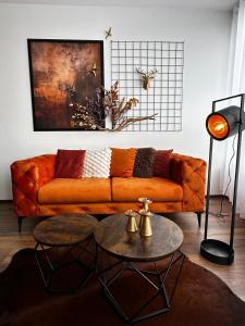 an orange couch in a living room with two tables at Orange byt s parkovacím místem v centru města in České Budějovice