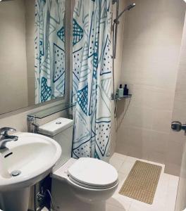 La salle de bains est pourvue d'un lavabo, de toilettes et d'un rideau de douche. dans l'établissement Man-made beach waves 19 minutes from NAIA, à Manille