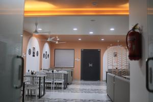 a dining room with tables and chairs and a screen at Hotel Siddhesh INN in Pimpalwandi