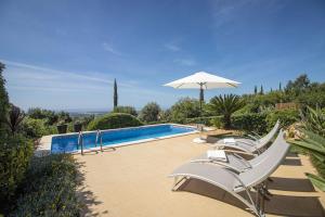 a group of white chairs and an umbrella next to a swimming pool at Villa Vista in Valados