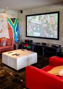 un salon avec une grande télévision et des meubles rouges dans l'établissement Misverstand Boutique Farm Lodge, à Potchefstroom