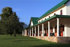 L'Heritage Retreat في Wildernis: مبنى بسقف أخضر وميدان عشبي