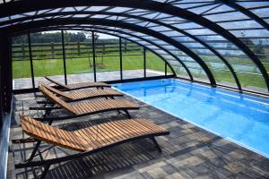 a group of chairs sitting next to a swimming pool at Leśny Zakątek Uroczysko -Apartamenty Nowoczesnej Stodoły in Stogniewice