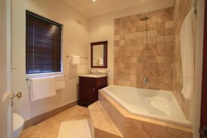 L'Heritage Retreat في Wildernis: حمام كبير مع حوض استحمام ومغسلة