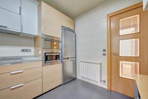 eine Küche mit Edelstahlkühlschrank und Holzschränken in der Unterkunft El Encanto de Huesca by Clabao in Logroño