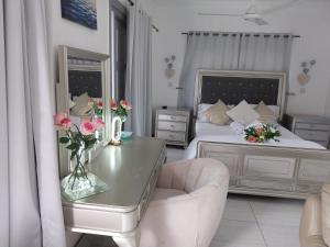 a bedroom with a bed and a table with flowers on it at Agnes Cottage in La Réunion