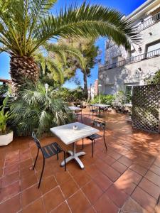 a patio with tables and chairs and palm trees at Hotel Oreneta in Altafulla