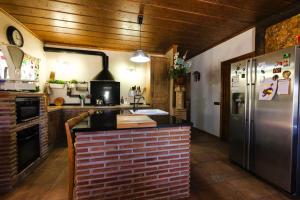 eine Küche mit einer Backsteintheke und einem Kühlschrank in der Unterkunft Casa rural con barbacoa y piscina in Ríogordo