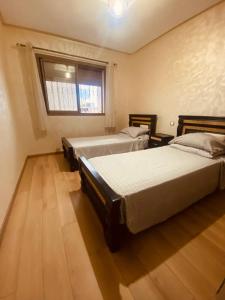 モハメディアにあるCharmant appartement joyau du parc 200m plageのベッド2台と窓のある寝室