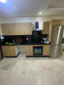 モハメディアにあるCharmant appartement joyau du parc 200m plageのキッチン(ステンレス製の冷蔵庫、木製キャビネット付) +4枚の写真