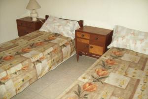 a bedroom with two beds and a dresser and a night stand at Muras Apart Hotel in Mendoza