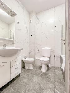 a white bathroom with a toilet and a sink at Nordic Residence NH 42 in Suceava +15 photos