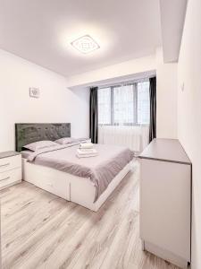 a white bedroom with a bed and a window at Nordic Residence NH 42 in Suceava