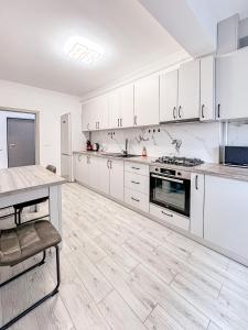 a large kitchen with white cabinets and a table at Nordic Residence NH 42 in Suceava