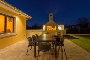 a dining table and chairs on a patio at night at Villa Brajde by IstriaLux in Gajana