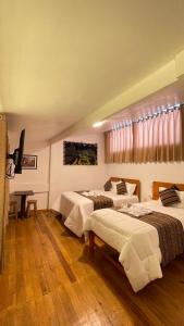 a hotel room with two beds and a television at La casa de Goya in Cusco