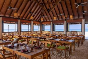 Un comedor con mesas y sillas de madera. en Dhigufaru Island Resort, en Atolón Baa