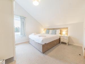 een witte slaapkamer met een groot bed en een raam bij Beech - Woodland Cottages in Bowness-on-Windermere