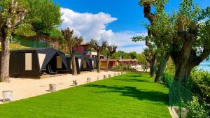 a row of tents on a beach with trees and grass at Campeggio della Colombaia in Padenghe sul Garda