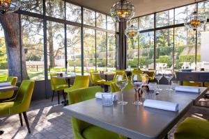 a dining room with a table and chairs and large windows at Maison D'Anthouard in Écully