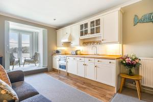 a kitchen with white cabinets and a table with flowers at No 26 The Salcombe in Salcombe