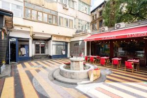 a fountain in the middle of a street with tables and chairs at Sunset - Luxury Studio on Calea Victoriei in Bucharest +22 photos