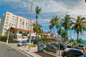 a street with cars parked in front of a building at Casa Circuito Carnaval frente à praia in Salvador
