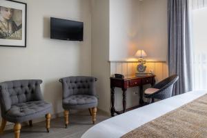 a hotel room with a bed and two chairs and a desk at Hotel Ter Duinen in Bruges