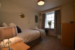 a bedroom with a bed with a window and a lamp at Duke's House, Penrith - Stunning Large Home - Town Centre on your Doorstep - 5 Bedrooms & Sun Trap Garden - Lake District Stay in Penrith