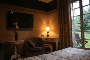 een slaapkamer met een bed, een stoel en een televisie bij Hôtel Beatus in Cambrai