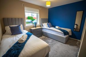a bedroom with two beds and a blue wall at Bonnie Apartment in Coatbridge