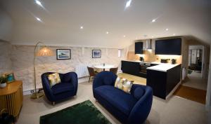 a living room with two blue chairs and a kitchen at Katie Ann's Thatched Cottage in Luib