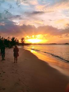 two people walking on the beach at sunset at River House in Marau
