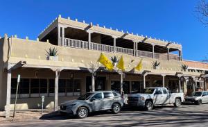 two cars parked in front of a building at Palace Modern Hotel at the Plaza in Santa Fe