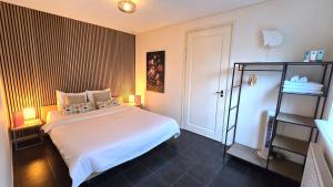 a bedroom with a large white bed and a shelf at DJP76 mooi gelijkvloers appartement met terras in Domburg +5 photos