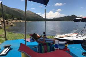 una persona tendida en una silla junto a un barco en Magical Lake Cabin - Ski Shack, en Camacorinto