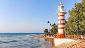 a lighthouse on a beach next to the ocean at surf in Paracuru