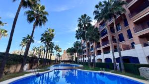 a swimming pool in front of a building with palm trees at Vilamar VyB in Denia +11 photos