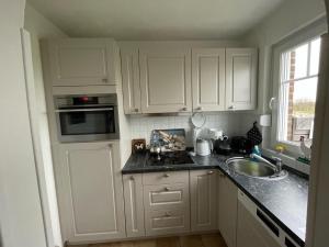 a kitchen with white cabinets and a sink at Ferienwohnung Wiesenblick in Westerland (Sylt) +17 photos