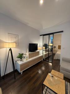 een woonkamer met een televisie en een woonkamer met een bank bij Apartamento Azonaicas in Córdoba
