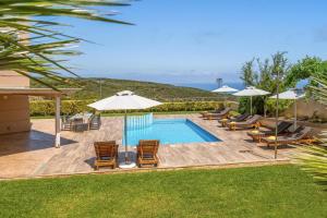 une piscine avec chaises longues et parasols dans l'établissement Villa Ariella With Sea View, à Agia Marina