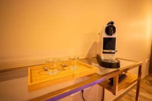 a coffee maker and two glasses on a glass table at Spa beige room in Berstett