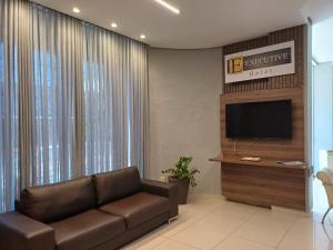 a living room with a couch and a flat screen tv at Executive Hotel MT in Lucas do Rio Verde