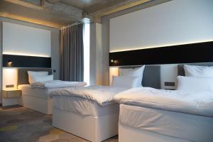two beds in a hotel room with white sheets at Olive INN Berlin in Berlin