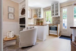 a kitchen with white cabinets and a chair and a table at GÄSTEWOHNUNGEN AM SEE "Maisonette & Suite" in Neuenkirchen