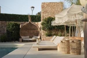 a patio with chairs and umbrellas next to a pool at Mar Suites Formentera by Universal Beach Hotels in Es Pujols